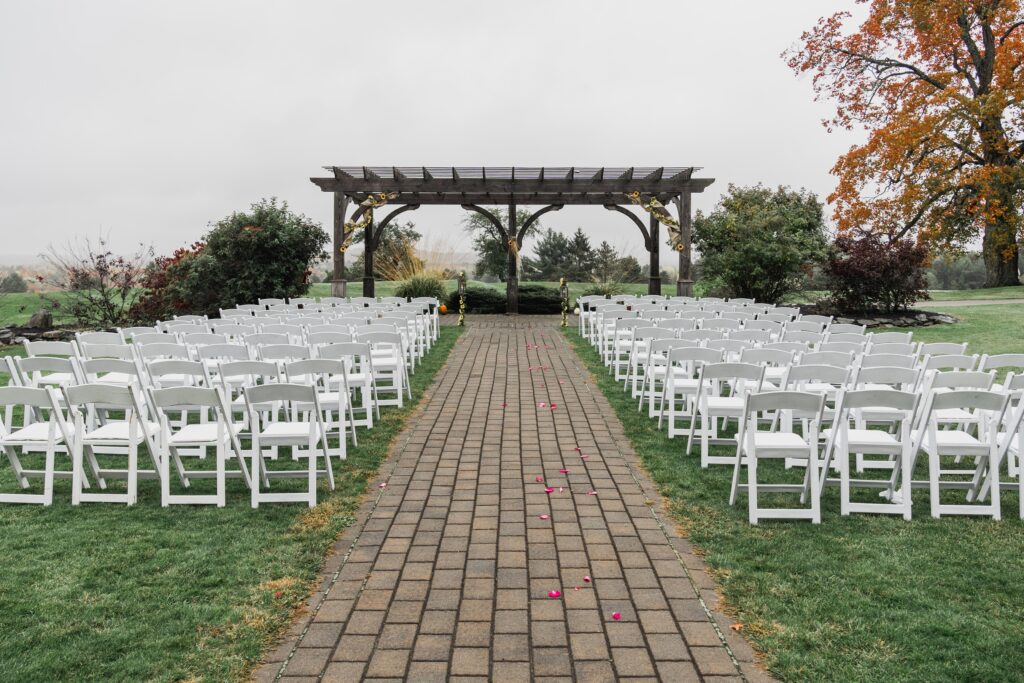 photo of wedding ceremony venue outside with arches and folding chairs