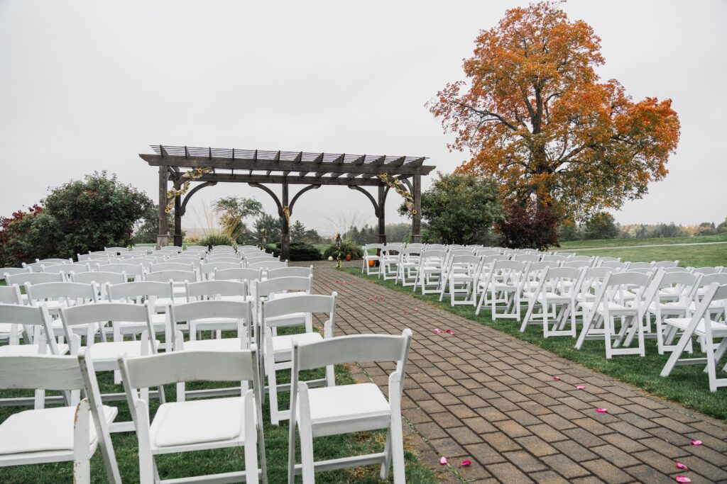 photo of wedding ceremony venue outside with arches and folding chairs